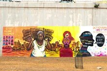 Une fresque murale féministe colorée peinte sur un grand mur en béton à Dakar, illustrant des messages et des portraits de femmes africaines engagées.