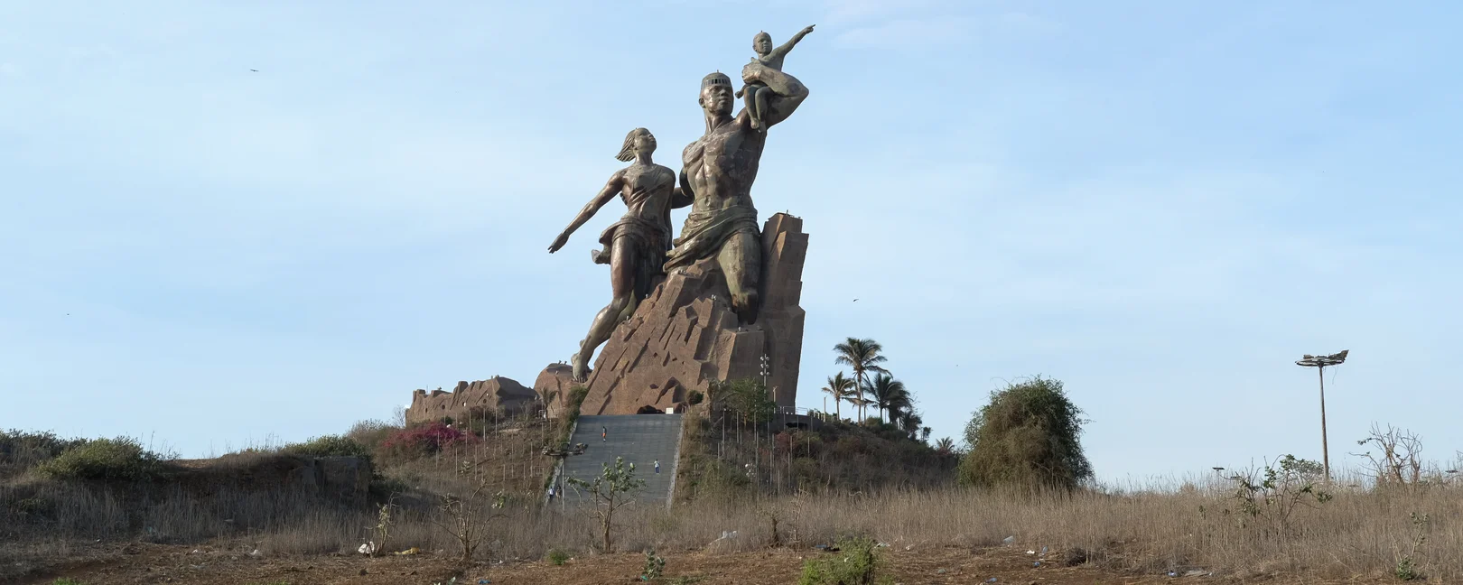 Le Monument de la Renaissance africaine à Dakar, une immense statue en bronze représentant une famille sur une colline sous un ciel clair.