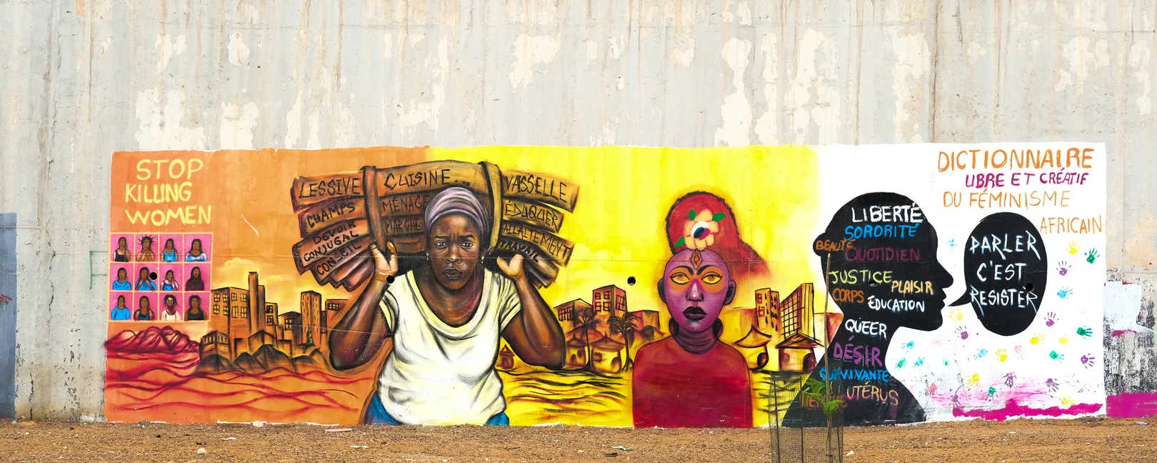 Une fresque murale féministe colorée peinte sur un grand mur en béton à Dakar, illustrant des messages et des portraits de femmes africaines engagées.