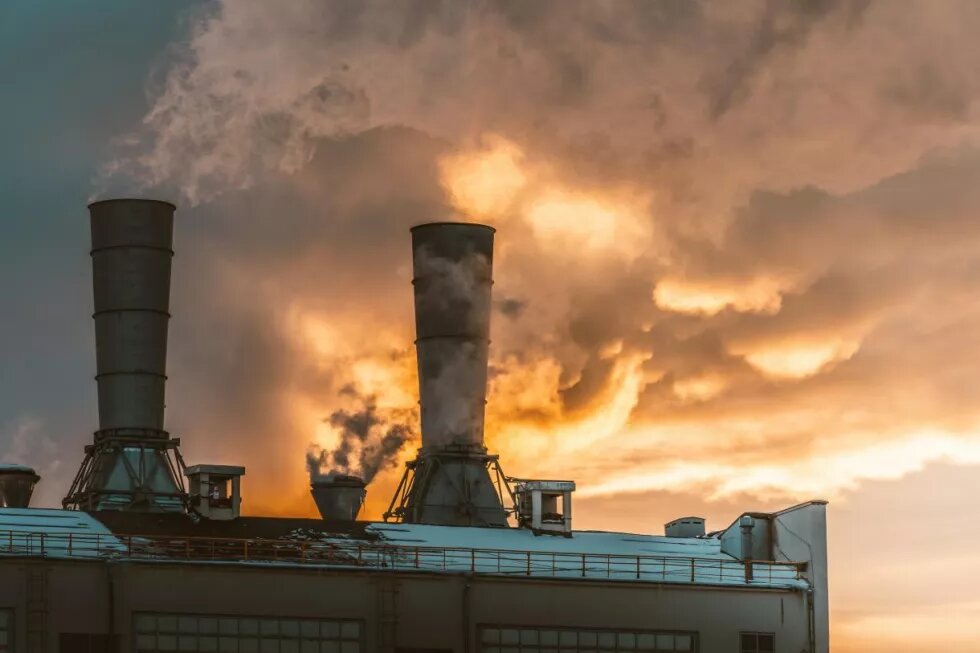 Toit d'une usine, dont les cheminées dégagent de la fumée