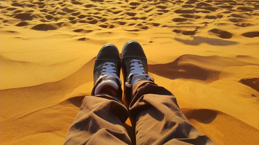 homme assis dans le sable du desert