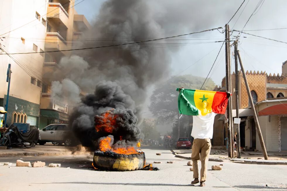 Un jeune brandissant son drapeau à côté d'un pneu en feu. Le hashtag #freeSenegal a été souvent utilisé pendant les manifestations.